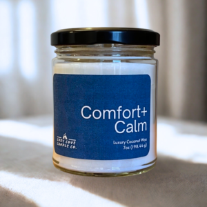 7 oz comfort and calm candle sitting on a table with window in the background